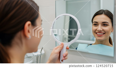 Patient smiling in mirror after dental treatment in bright modern clinic setting 124520715