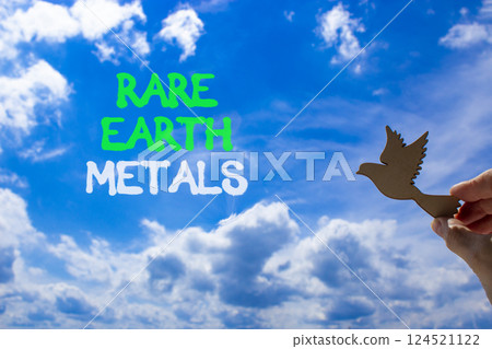Rare earth metals symbol. Concept words Rare earth metals. Beautiful blue sky clouds background. Businessman hand, wooden birds. Business and rare earth metals concept. Copy space. 124521122
