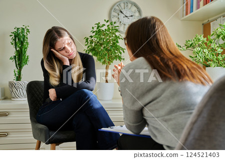 Sad unhappy young woman at therapy with female professional psychologist 124521403