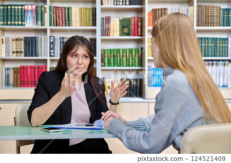 Professional psychologist female working with young girl patient, sitting together in office Professional psychologist female working with young girl patient, sitting together in office 124521409