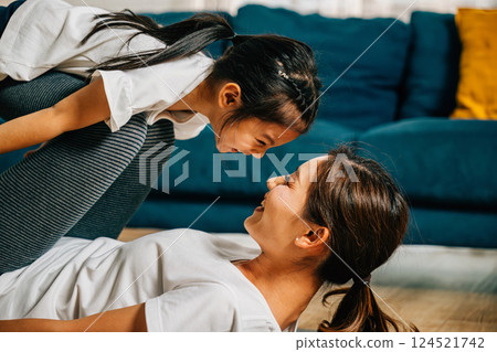 In their home a mother and her child embrace the fun of family fitness pretending to 'fly' like airplanes during Pilates and yoga strengthening their bond and sharing happiness. 124521742