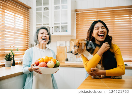 A happy Asian grandmother, her daughter, and young woman share a playful kitchen scene with their Beagle dog, highlighting the fun, happiness, and family bonding over pet care. A happy Asian grandmother, her daughter, and young woman share a playful kitchen scene with their Beagle dog, highlighting the fun, happiness, and family bonding over pet care. 124521763