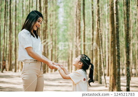 Asian mother and daughter walking hand in hand through a forest, Happy mother and little child holding hands together, Family day 124521783