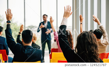 During a corporate event businesspeople in a conference and convention engage in discussions. Raised hands demonstrate active participation in a meeting training seminar and teamwork. During a corporate event businesspeople in a conference and convention engage in discussions. Raised hands demonstrate active participation in a meeting training seminar and teamwork. 124521787