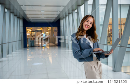Businesswoman multitasking on laptop and cellphone in park, balancing work and relaxation in a green urban space 124521803