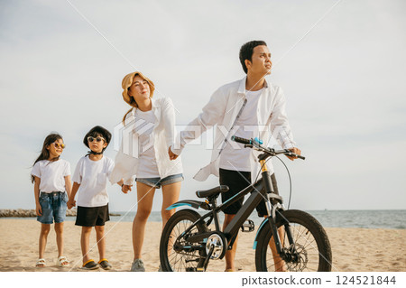 Parents and children walking with bicycles on the beach a full-length scene of family happiness smiles and the carefree spirit of childhood. Family on beach vacation 124521844
