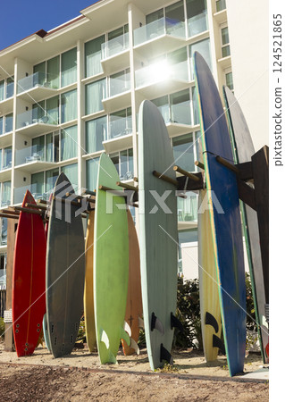 Many Surfboards On Stand Outdoor. Colorful Soft Foam And Wooden Construction Classic Surfboard Longboard Or Malibu. Vertical. Sunny Day, Seashore Or Ocean. Nobody. No People. Many Surfboards On Stand Outdoor. Colorful Soft Foam And Wooden Construction Classic Surfboard Longboard Or Malibu. Vertical. Sunny Day, Seashore Or Ocean. Nobody. No People. 124521865