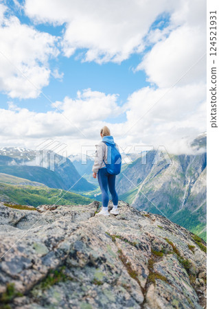 Young athletic girl standing on a rock with a backpack. Mountain valley. Travel and adventure 124521931
