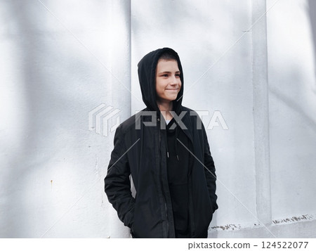 Young, cool, happy guy he wear black hoody casual clothes look away from the camera. Lifestyle concept. Photo of a handsome teenage boy in a sweatshirt with a black hood outdoors Young, cool, happy guy he wear black hoody casual clothes look away from the camera. Lifestyle concept. Photo of a handsome teenage boy in a sweatshirt with a black hood outdoors 124522077