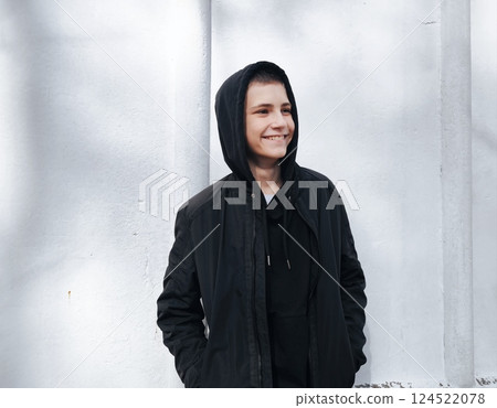 Young, cool, happy guy he wear black hoody casual clothes look away from the camera. Lifestyle concept. Photo of a handsome teenage boy in a sweatshirt with a black hood outdoors Young, cool, happy guy he wear black hoody casual clothes look away from the camera. Lifestyle concept. Photo of a handsome teenage boy in a sweatshirt with a black hood outdoors 124522078
