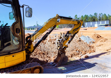 Heavy excavator machinery is actively digging into ground at construction site 124522957