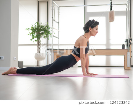 Asian woman doing upward facing dog exercise. Yoga class. Asian woman doing upward facing dog exercise. Yoga class. 124523242