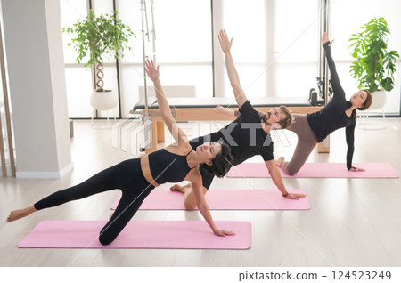 Two women and a man are doing yoga in the studio. Two women and a man are doing yoga in the studio. 124523249