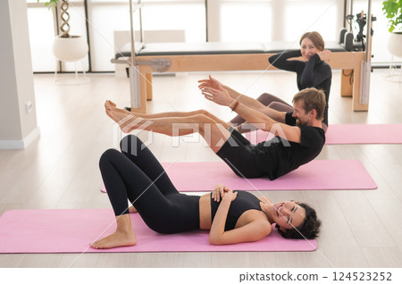 Two women and a man are doing yoga in the studio. 124523252