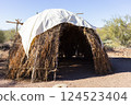 Native American Traditional Dwelling: Wigwam House, Home in Desert, Blue Sky and Bushes on Background. No People. Nature in USA. Building Structure.  124523404