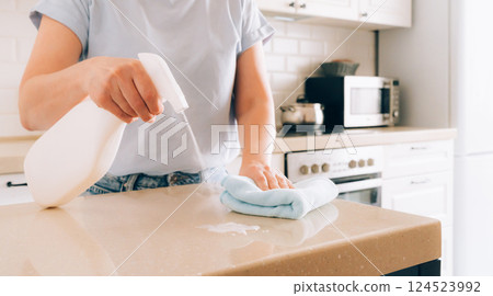 Female adult cleaning kitchen counter with spray bottle and cloth 124523992