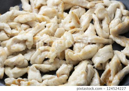 A cooking scene where chicken breast is fried in a frying pan. 124524227