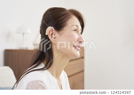 Senior woman wearing a hearing aid in living room 124524397