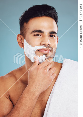 Face, beauty and shave with a man model in studio on a blue background for shaving or grooming. Portrait, skincare and hair removal with a handsome young male shaving his beard in the bathroom 124524563