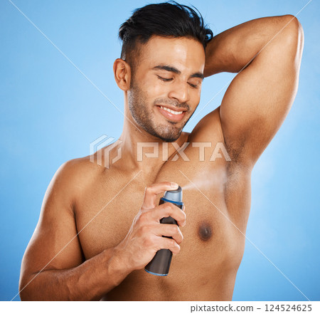 Deodorant, beauty and grooming with a man model using antiperspirant in studio on a blue background. Body spray, aerosol and smell with a handsome young male spraying a scent product to his underarm Deodorant, beauty and grooming with a man model using antiperspirant in studio on a blue background. Body spray, aerosol and smell with a handsome young male spraying a scent product to his underarm 124524625