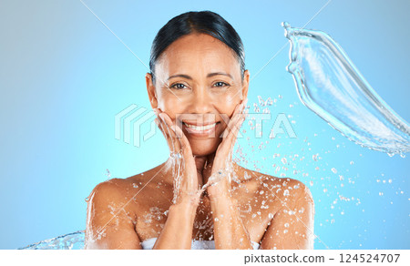 Beauty, splash and water with portrait of woman for skincare, shower and wellness. Hydration, fresh and hygiene with mature face model for luxury, relax and spa against a blue background in studio 124524707