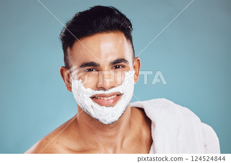 Face, beauty and shaving with a man model in studio on a blue background for wellness or grooming. Portrait, skincare and hair removal with a handsome young male in the bathroom to shave his beard 124524844