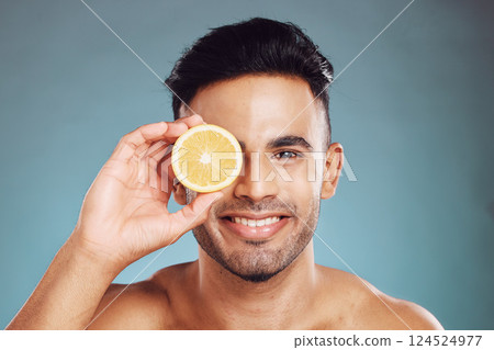 Happy studio portrait, man lemon skincare for beauty wellness and face health against blue backdrop. Young happiness model, cosmetic fruit for healthy facial skin or vitamin c with wall background Happy studio portrait, man lemon skincare for beauty wellness and face health against blue backdrop. Young happiness model, cosmetic fruit for healthy facial skin or vitamin c with wall background 124524977