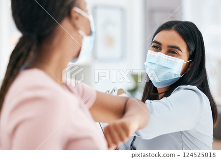 Covid, elbow bump and employees greeting while wearing face mask in office for teamwork and collaboration. Business women social distancing during covid 19 in a clean, diversity and coworking office 124525018