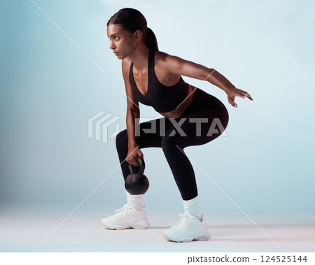 Black woman, kettlebell and exercise for wellness, focus or motivation for health, fitness and studio background. Female trainer, training and athlete being healthy for workout, strong and sportswear 124525144