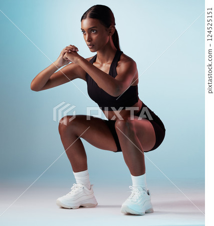 Exercise, sports and fitness model in studio doing a squat workout with motivation in sportswear. Strong, sport and slim woman athlete from India training for health while isolated by blue background 124525151