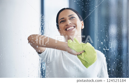Cleaning, glass and hygiene with a black woman using a cloth or rag while wiping a window in an office. Cleaner, janitor or housekeeper washing a transparent surface with soap and water 124525184