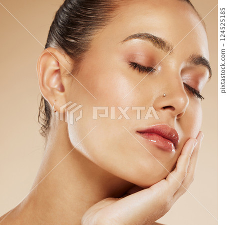 Makeup, beauty and face of a woman with a glow from cosmetics against a brown studio background. Skin, care and young cosmetic model touching facial art with natural glam for facial elegance 124525185