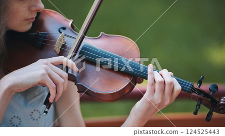 A young girl plays the violin in the city park. A young girl plays the violin in the city park. 124525443