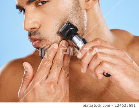 Beauty, skincare and man shaving beard in his grooming routine with an electric machine in a studio in Mexico. Wellness, Latino and healthy male model shaves his facial hair with a cool modern razor 124525691