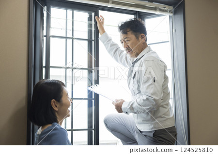 A worker inspecting a bay window sash A worker inspecting a bay window sash 124525810