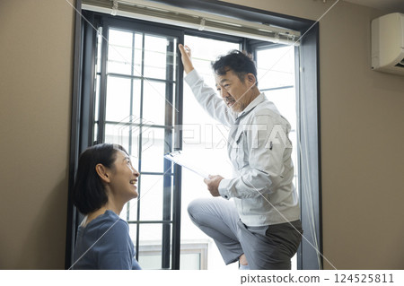 A worker inspecting a bay window sash 124525811