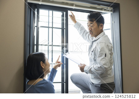 A worker inspecting a bay window sash A worker inspecting a bay window sash 124525812