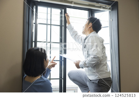A worker inspecting a bay window sash 124525813
