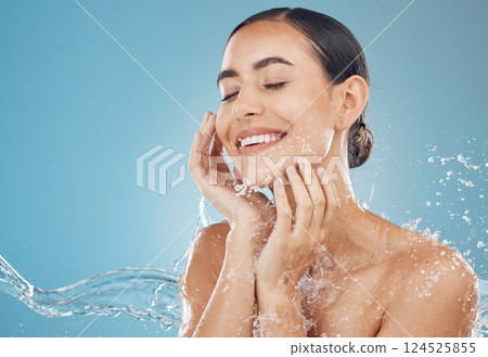 Beauty, skincare and splash of water with woman for wellness, hydration and fresh spa. Relax, smile and health with girl against blue background with mock up for luxury, natural cosmetics and shower 124525855