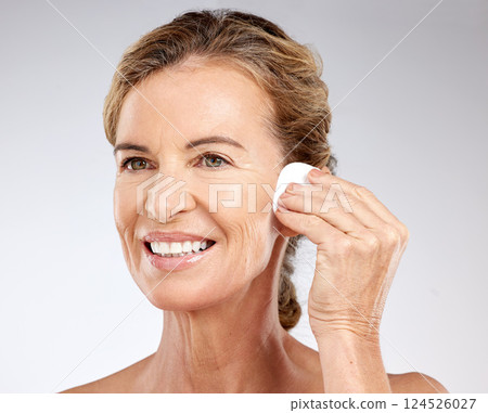 Skincare, cotton pad and senior woman with facial care against a grey studio background. Happy, smile and elderly model with luxury cosmetics for cleaning of skin, spa wellness and face beauty 124526027