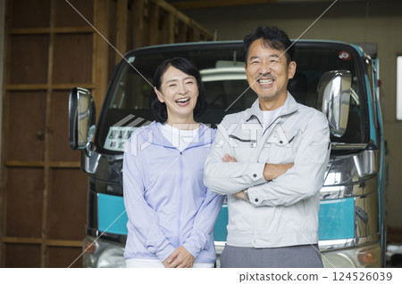A couple who run a construction company standing in front of a truck 124526039