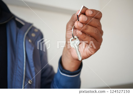 Man holding keys indoors in a casual setting while smiling 124527150