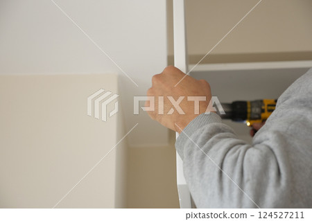 Person assembling furniture with power drill in modern interior Person assembling furniture with power drill in modern interior 124527211