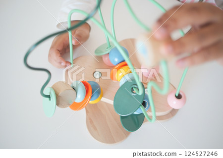 Hands engaged in colorful wooden bead activity for young children 124527246