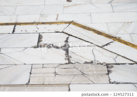 Cracked marble floor with a yellow line in an indoor space Cracked marble floor with a yellow line in an indoor space 124527311