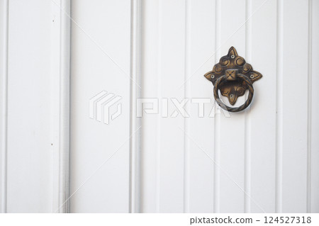 Decorative brass door knocker on a white wooden door 124527318