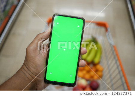 Holding a smartphone with a green screen in a grocery store 124527371