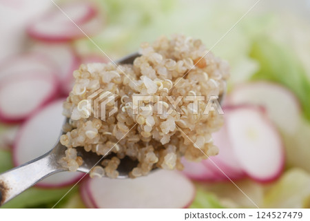 Quinoa on a spoon above sliced radishes and vegetables 124527479