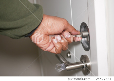 Hand unlocking a door at home in the evening 124527484
