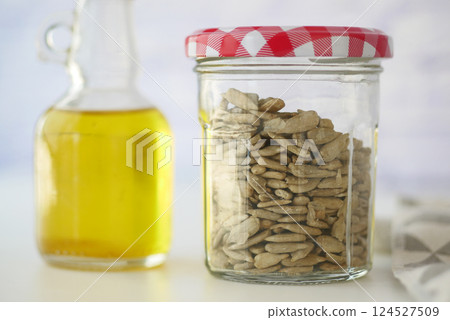 Sunflower seeds in jar beside bottle of oil on kitchen table Sunflower seeds in jar beside bottle of oil on kitchen table 124527509